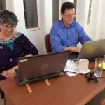 Kate monitors the Greek and English texts, while Andy recommends changes.